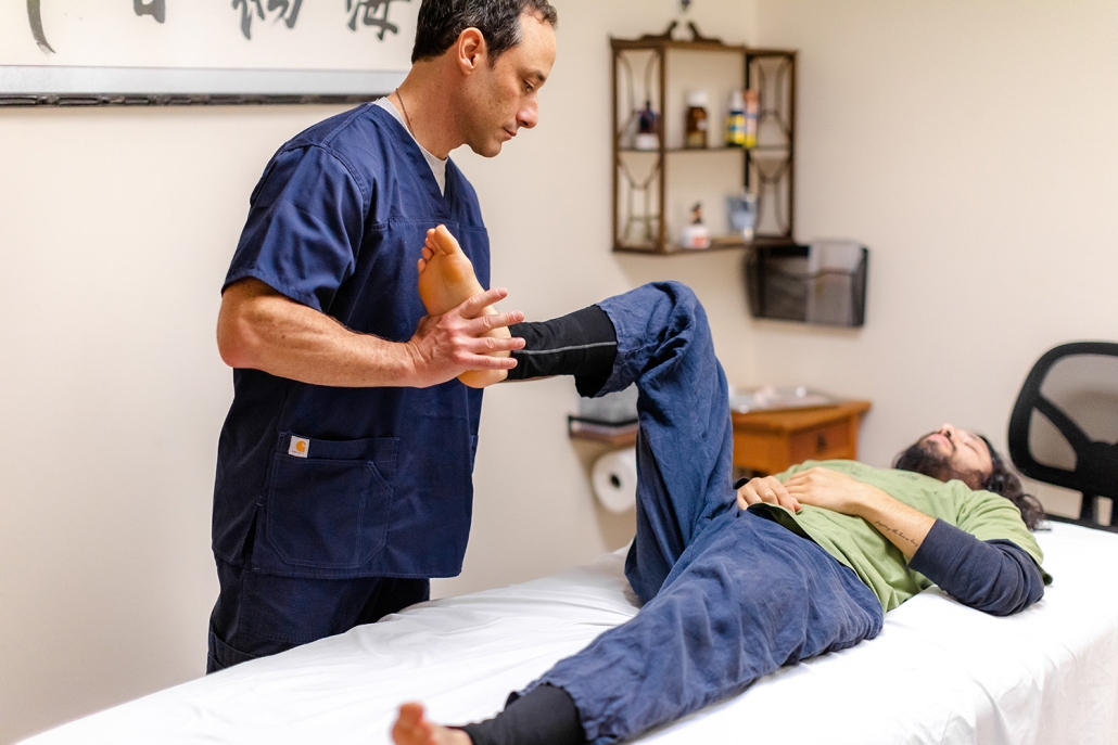 Shen Dao Clinic practitioner lifting a patient's leg